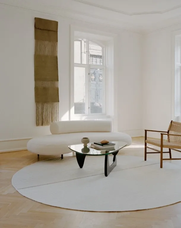 Rundt lyst tæppe med sofa og vævet vægtekstil