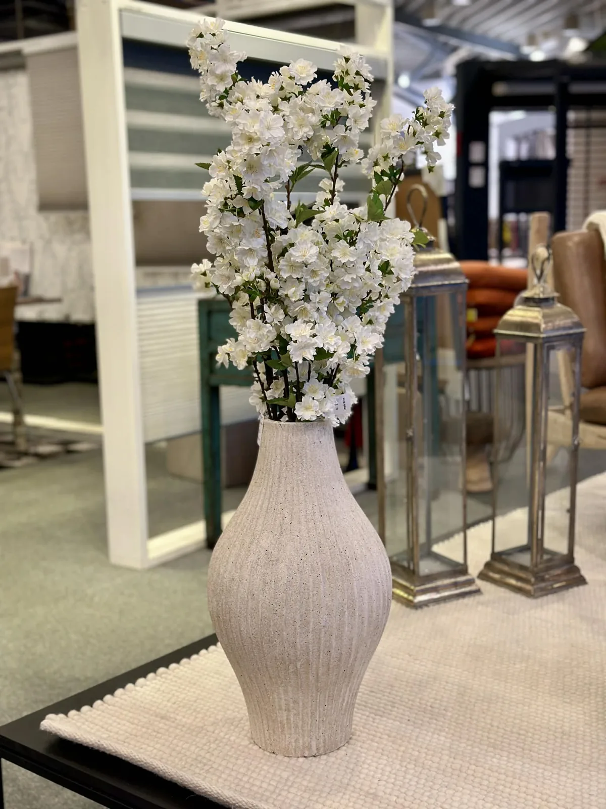 Høj vase med blomstergrene mellem spejle i showroomet